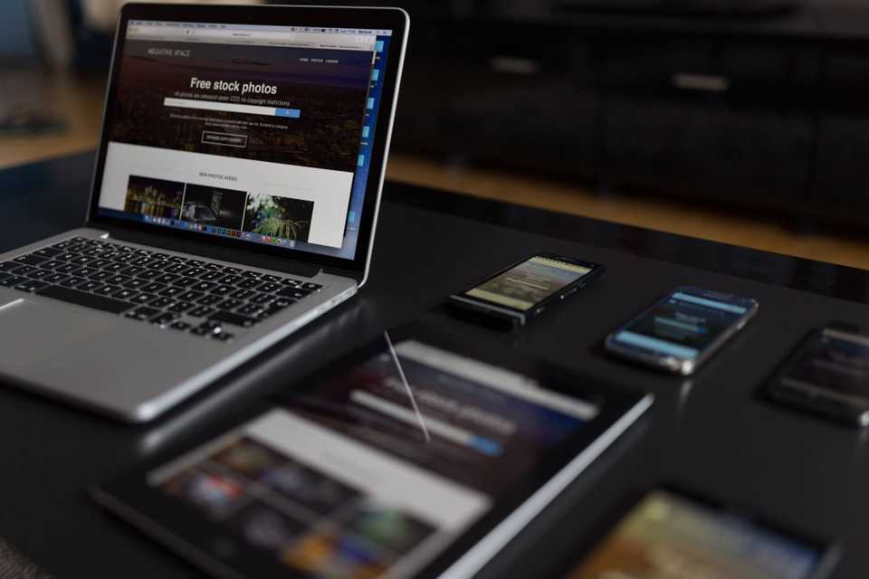 Vários dispositivos exibindo o mesmo site: um notebook, quatro smarthphones e um tablet.