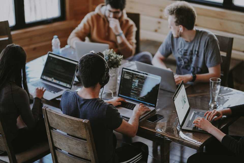 Cinco desenvolvedores trabalhando juntos em uma mesa.